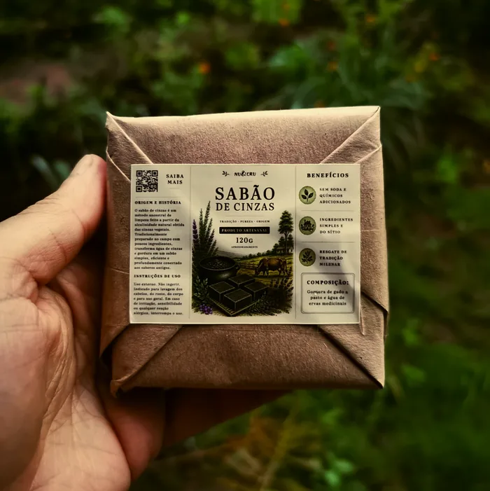 Mão segurando o Sabão de Cinzas Nu&Cru embalado em papel kraft