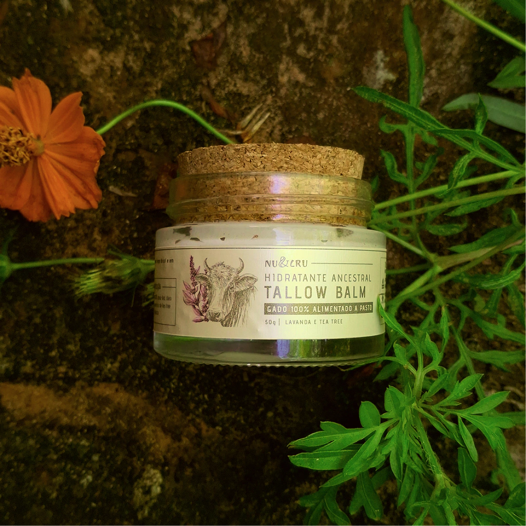 Pote de vidro de Tallow Balm Nu&Cru com tampa de cortiça, entre flores laranjas e folhagem